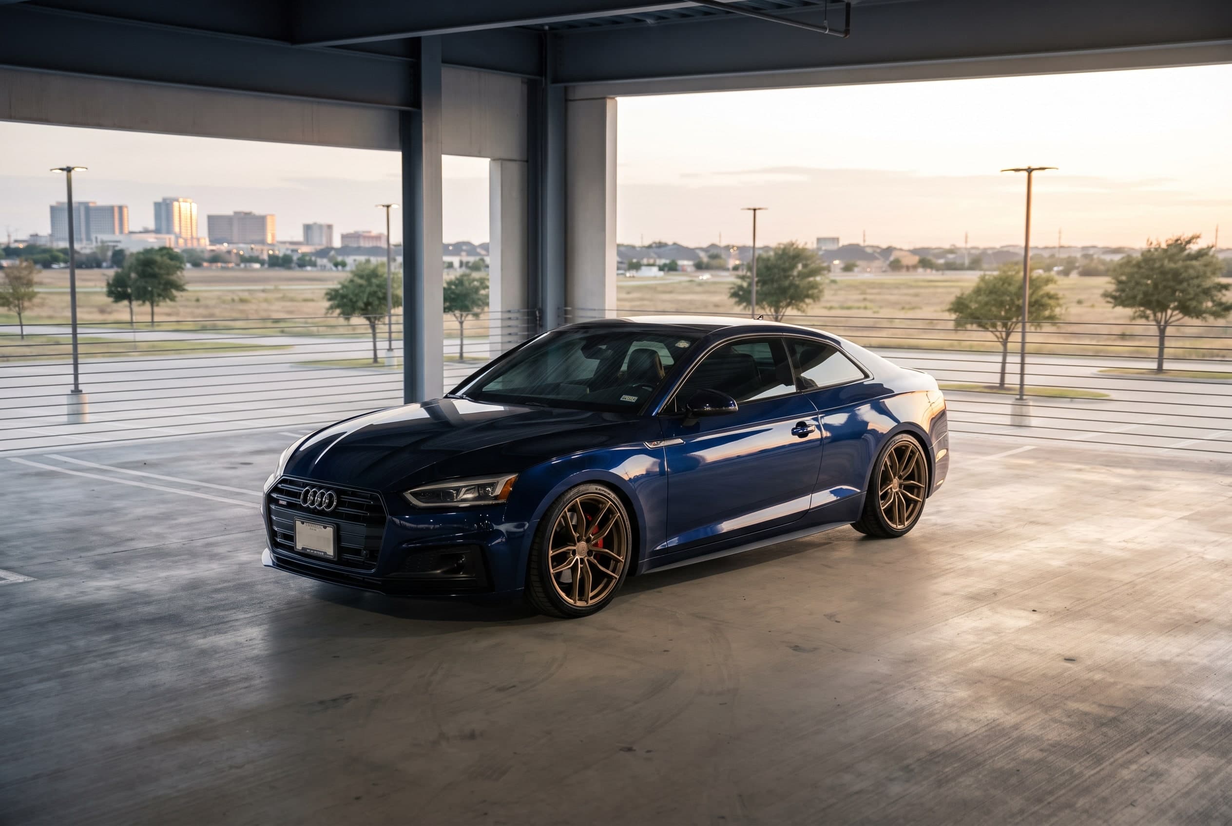 Bronze flow-formed 19-inch wheels on a lowered blue Audi A5 in a Las Colinas parking garage